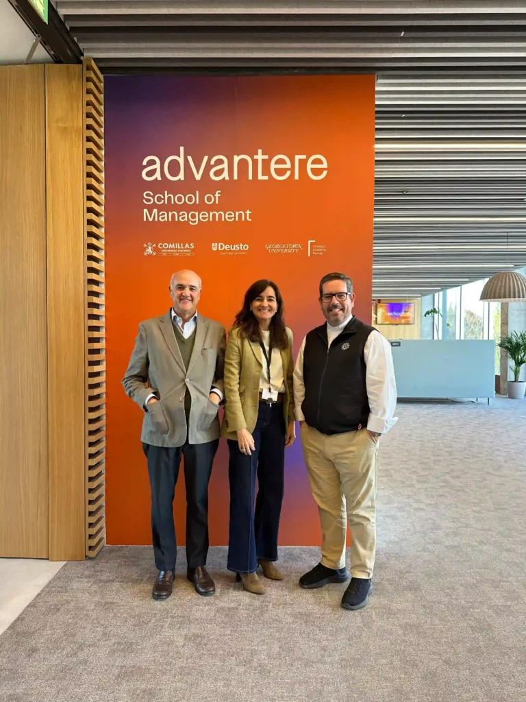 Three people standing together at Advantere School of Management, posing in front of the institutional welcome wall at the campus.