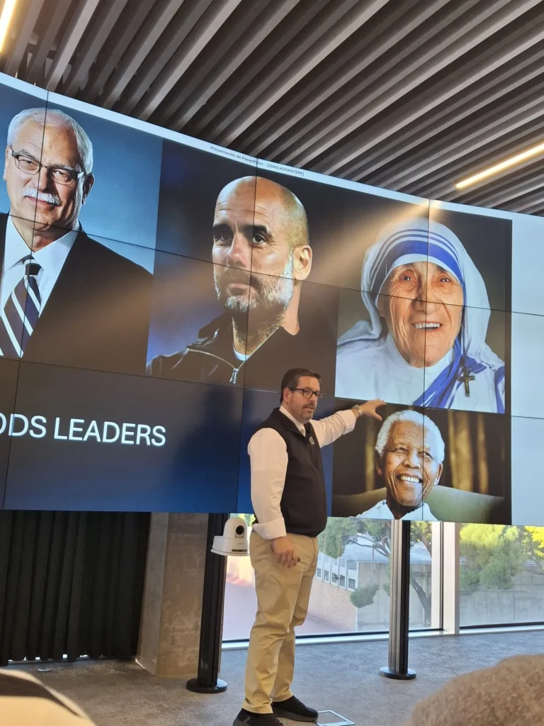 Fr. Javier Bailén presenting a leadership lecture at Advantere, pointing to examples of inspirational figures displayed on the screen